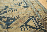 Intricate geometric patterns in dark navy, sand, and seafoam blue on an antique Caucasian rug.
