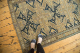 Geometric navy and sand patterns on an antique Caucasian rug, with visible edge wear.