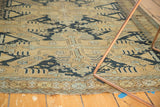 Lower border detail of antique Caucasian rug with sand, navy, light blue geometric patterns and tattered edge.