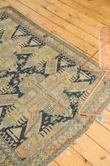 Antique Caucasian rug corner detail revealing geometric border, dark navy patterns, and worn fringe.