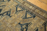 Geometric patterns in sand, dark navy, and mauve with wear across knot heads.