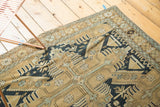 Antique Caucasian rug corner with geometric pinwheel motifs in sand, navy, and seafoam.