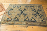 Sand, dark navy, and seafoam blue geometric patterns on an antique Caucasian rug edge.