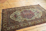 Antique Kermanshah rug's lower section displaying cochineal red Safavid borders and beige floral vinery.