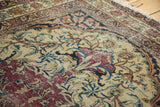 Safavid-inspired red arabesque border framing intricate floral vinery on ivory field.