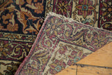 Antique Kermanshah rug's reverse, showing hand-knotted foundation, tattered ends, and worn pile.