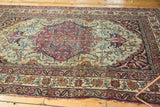 Antique Kermanshah rug's Safavid borders, sprawling floral vinery, cochineal red, and tattered edge.