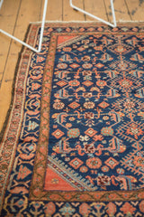 Engelas rug corner with indigo field, Herati motif, scattered birds, and terra cotta border.