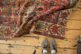 Antique Malayer rug folded, faded red floral vinery and beige border with celadon green motifs.