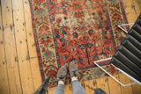 Antique Persian Malayer rug with faded madder root red field, floral vinery, and visible wear.