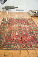 Detailed corner of antique Malayer rug, blush red field, rectilinear floral, celadon border, and fringe.