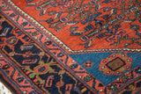 Intricate brick red Herati motif and sapphire blue spandrel on an Engelas rug corner.