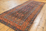 Antique Kurdish Bijar runner showing allover henna plant motif and vibrant floral border.