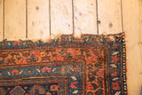 Tattered end of an antique Kurdish Bijar rug runner, showcasing geometric and floral motifs.