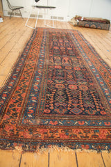 Frayed end of Antique Kurdish Bijar runner, showing tatter, navy, and rust floral motifs.