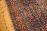 Tattered side edge and geometric border of antique Kurdish Bijar runner in navy, red, and orange.