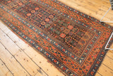 Hard tatter and holes at the end of an antique Kurdish Bijar runner, revealing floral motifs.