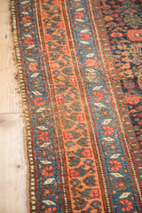 Antique Kurdish Bijar runner's tattered edge with vibrant floral banded patterns.