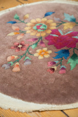 Art Deco round rug showing ivory plain weave edge and colorful stemmed floral pattern.