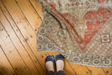 Distressed Oushak rug with dusty red geometric floral motifs and visible worn texture.