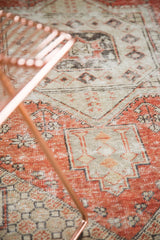 Distressed vintage Oushak rug with worn dusty red, charcoal, and ivory geometric patterns.