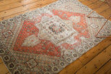 Distressed vintage Oushak rug detail showing dusty red, ivory geometric floral motifs.