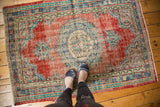 Distressed Oushak rug with faded cherry red, royal blue medallion, and visible knot heads.