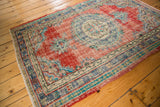 Distressed cherry red Oushak field, faded blue roundel medallion, and intricate mint border.