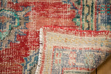 Vintage distressed Oushak rug corner revealing hand knotted construction, secured edge, and fringe.
