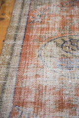 Pattern detail of distressed Oushak rug with faded ruby grapefruit, royal blue, and ivory threads.