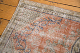 Close-up detail of a vintage distressed Oushak rug's pile, showing faded ruby grapefruit and visible foundation.