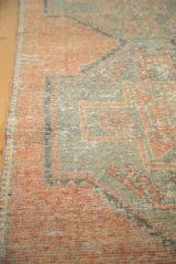 Distressed vintage Oushak runner fragment edge showing apricot and silver rectilinear patterns.