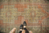 Distressed vintage Oushak runner with faded terra cotta, beige, and green pattern.