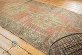 Decorative corner of vintage Oushak runner, distressed plant patterns in terra cotta and olive.