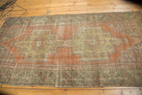 Distressed Oushak runner corner showcasing terra cotta field and beige plant motifs.