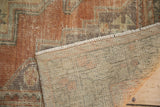 Distressed Oushak rug with faded terra cotta pile and visible hand-knotted beige foundation.