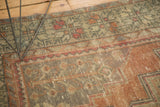 Distressed pile texture of a vintage Oushak runner, showing muted green and terracotta geometric motifs.