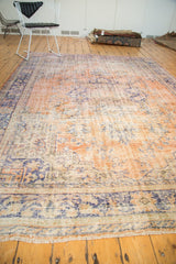 Distressed fringed end of the Oushak rug, showing worn peach, blue, and visible foundation.