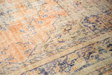 Distressed Oushak rug texture revealing worn pile, knot heads, and faded peach, blue patterns.