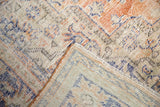 Distressed Oushak carpet showing worn pile, visible foundation, faded peach and blue tones.