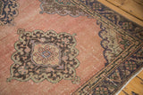 Distressed dusty apricot field, showing knot heads, and dark patterned borders of a Sparta rug.