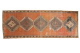Distressed vintage Oushak runner with geometric diamond medallions in faded copper and charcoal.