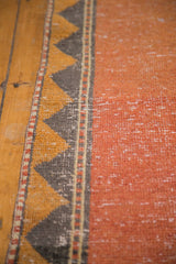 Distressed Oushak runner detail: faded burnt orange pile and geometric charcoal, dusty gold border.