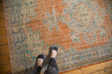 Distressed Oushak carpet displaying worn texture, faded tangerine, royal blue, and ivory.