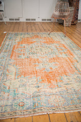 Close-up of distressed vintage Oushak rug showing worn pile, secured fringe, and faded tones.