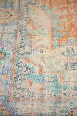 Worn pile and exposed foundation of a distressed Oushak rug in tangerine, blue, ivory.