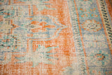 Distressed pile texture of the vintage Oushak rug, highlighting faded tangerine, blue, and ivory tones.