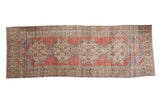 Vintage distressed Oushak runner featuring repeating medallions in faded red, blue, and ivory, 3'3