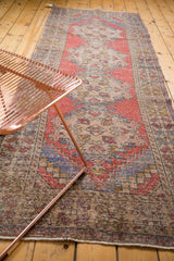 Distressed Oushak runner showing even wear, faded cherry red, and pale blue patterns.