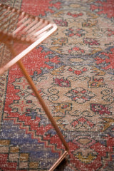 Distressed vintage Oushak rug texture, showing faded cherry red, pale blue, and ivory.